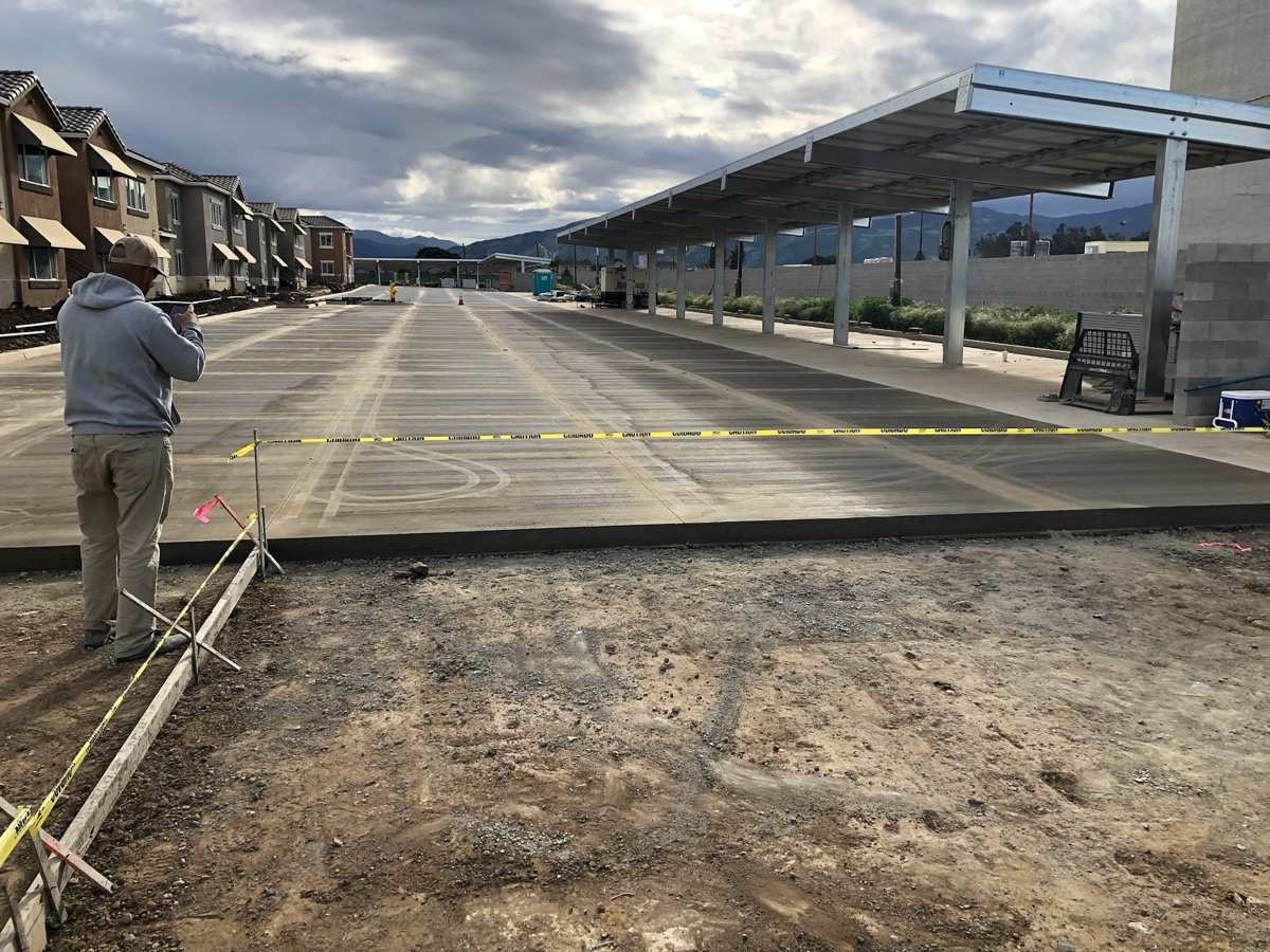Finished commercial concrete pad beside covered parking
